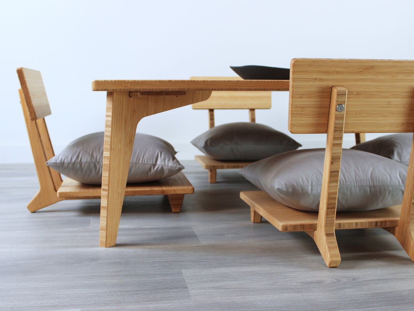 Large Square Low Table with a natural bamboo finish and midcentury modern design. Four Floor Chair Comfort with grey pillows are set at the table. Small black pottery vessel placed on table top. 

Japandi, minimalist, mid-century, Japanese inspired, modern, contemporary, clean lines, organic design, sustainable bamboo, renewable bamboo, solid bamboo, eco-friendly furniture, natural materials, natural-based finish