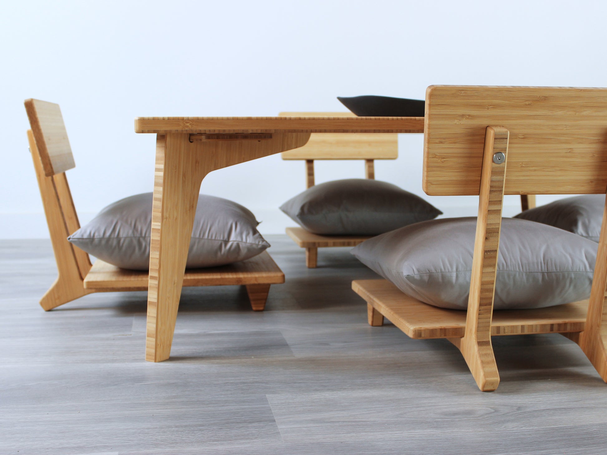 Large Square Low Table with a natural bamboo finish and midcentury modern design. Four Floor Chair Comfort with grey pillows are set at the table. Small black pottery vessel placed on table top. 

Japandi, minimalist, mid-century, Japanese inspired, modern, contemporary, clean lines, organic design, sustainable bamboo, renewable bamboo, solid bamboo, eco-friendly furniture, natural materials, natural-based finish