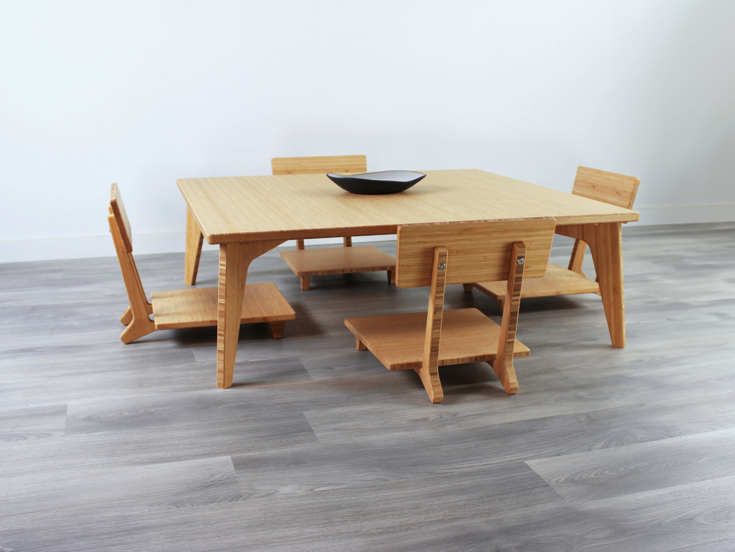 Large Square Low Table with a natural bamboo finish and midcentury modern design. Four Floor Chair Comfort with grey pillows are set at the table. Small black pottery vessel placed on table top. 

Japandi, minimalist, mid-century, Japanese inspired, modern, contemporary, clean lines, organic design, sustainable bamboo, renewable bamboo, solid bamboo, eco-friendly furniture, natural materials, natural-based finish