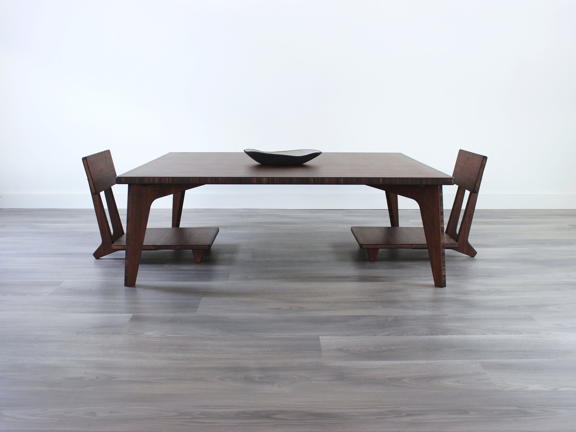 Large Square Low Table with a walnut bamboo finish and midcentury modern design. Two Floor Chair Comfort are set at the table. Small black pottery vessel placed on table top. 

Japandi, minimalist, mid-century, Japanese inspired, modern, contemporary, clean lines, organic design, sustainable bamboo, renewable bamboo, solid bamboo, eco-friendly furniture, natural materials, natural-based finish
