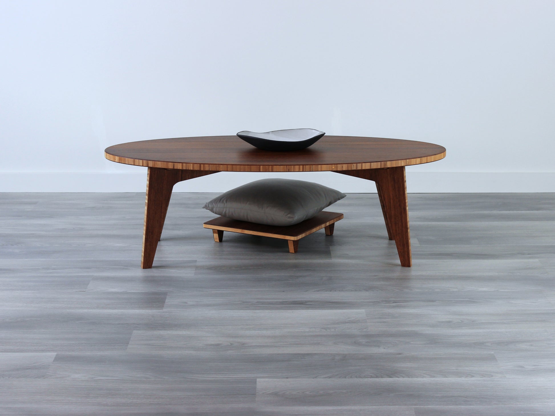 Oval LOW Table set with a chestnut bamboo finish and midcentury modern design. A Floor Chair Posture with grey pillow are set at the table. Small black pottery vessel placed on table top. 

Japandi, minimalist, mid-century, Japanese inspired, modern, contemporary, clean lines, organic design, sustainable bamboo, renewable bamboo, solid bamboo, eco-friendly furniture, natural materials, natural-based finish
