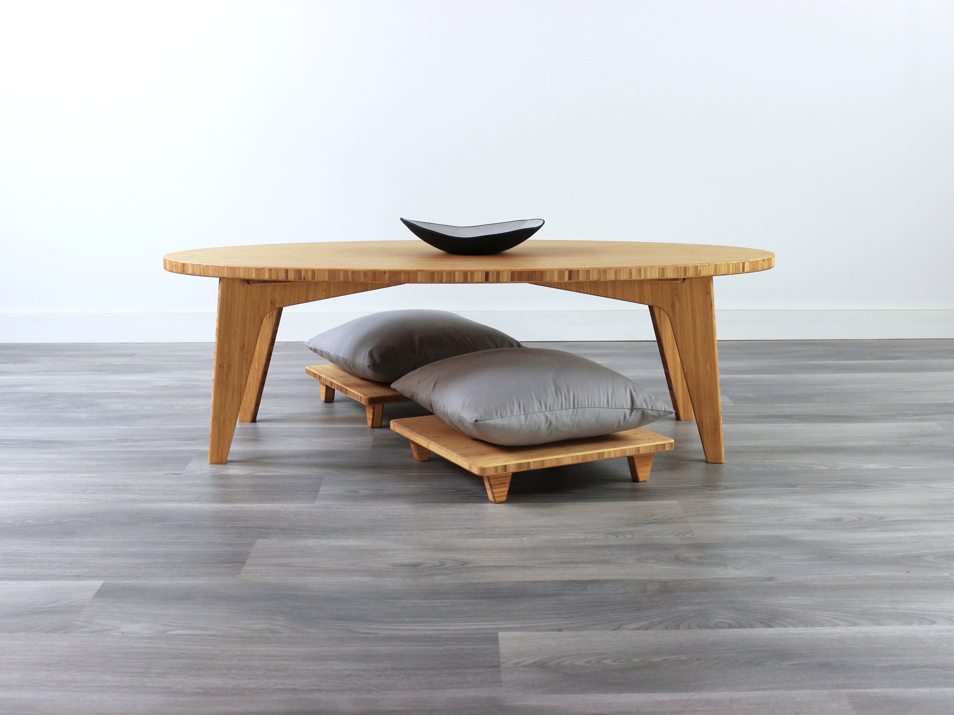 Oval LOW Table set with a natural bamboo finish and midcentury modern design. Two Floor Chair Posture with grey pillow are set at the table. Small black pottery vessel placed on table top. 

Japandi, minimalist, mid-century, Japanese inspired, modern, contemporary, clean lines, organic design, sustainable bamboo, renewable bamboo, solid bamboo, eco-friendly furniture, natural materials, natural-based finish
