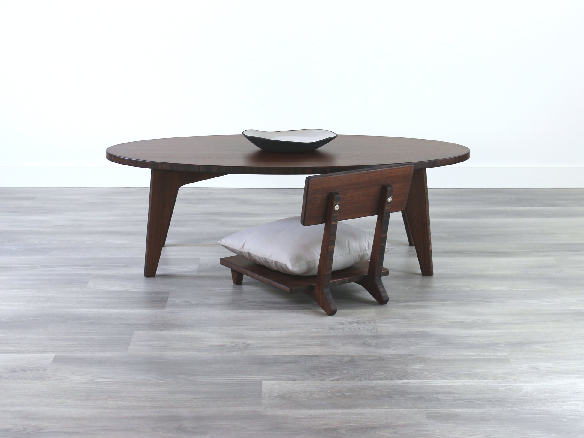 Oval LOW Table set with a walnut bamboo finish and midcentury modern design. A Floor Chair Comfort with grey pillow are set at the table. Small black pottery vessel placed on table top. 

Japandi, minimalist, mid-century, Japanese inspired, modern, contemporary, clean lines, organic design, sustainable bamboo, renewable bamboo, solid bamboo, eco-friendly furniture, natural materials, natural-based finish