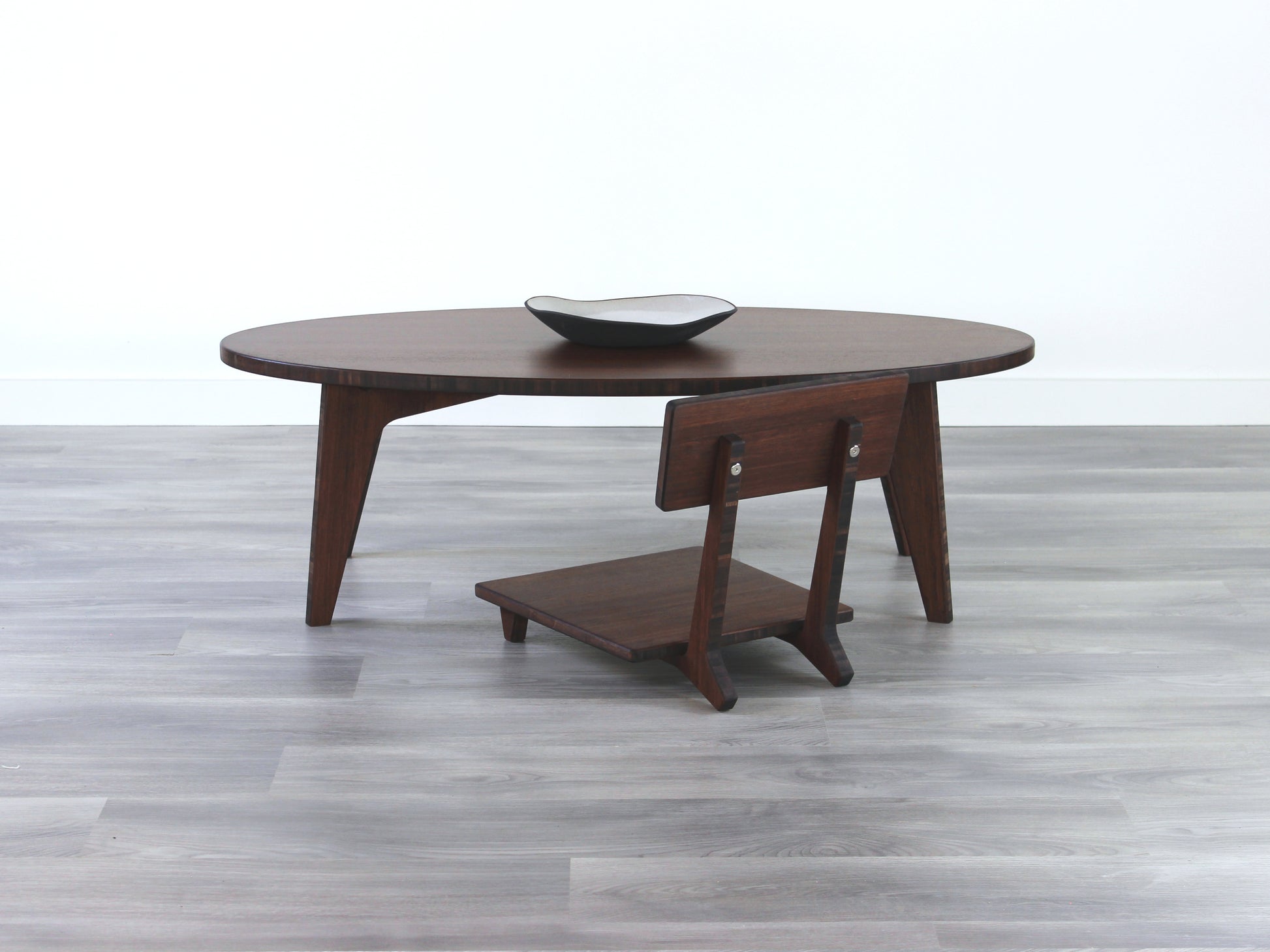 Oval LOW Table set with a walnut bamboo finish and midcentury modern design. A Floor Chair Comfort set at the table. Small black pottery vessel placed on table top. 

Japandi, minimalist, mid-century, Japanese inspired, modern, contemporary, clean lines, organic design, sustainable bamboo, renewable bamboo, solid bamboo, eco-friendly furniture, natural materials, natural-based finish