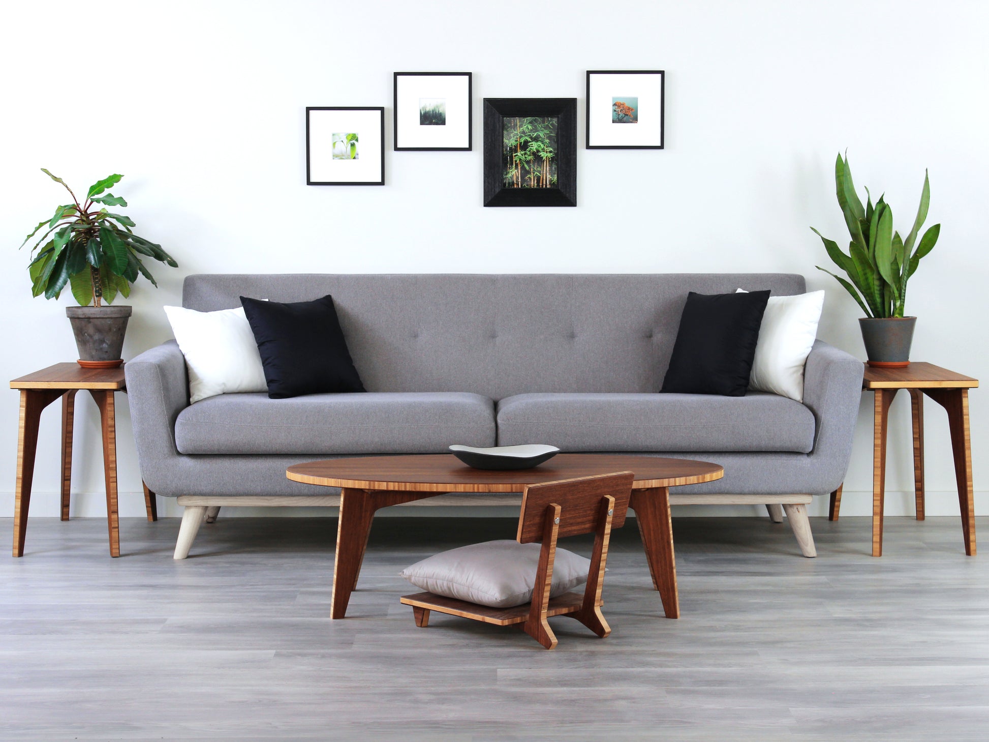 An oval-shaped bamboo table with a smooth, elongated surface and a warm finish. The table is placed on a grey floor, and it appears to have a small black and white pottery vessel on top. Set in a living room with a grey couch and photos on the white wall.

kotatsu
floor dining table
floor table
japan coffee table
japan furniture
japan table
chabudai
contemporary
