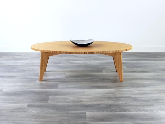 A oval-shaped bamboo coffee table with a smooth finish and curved legs, placed on a grey floor. Small black and white pottery vessel on top. 

mid century modern low table
midcentury modern coffee table
floor table
japan coffee table
japan furniture
japan table
oval coffee table 
bamboo low table