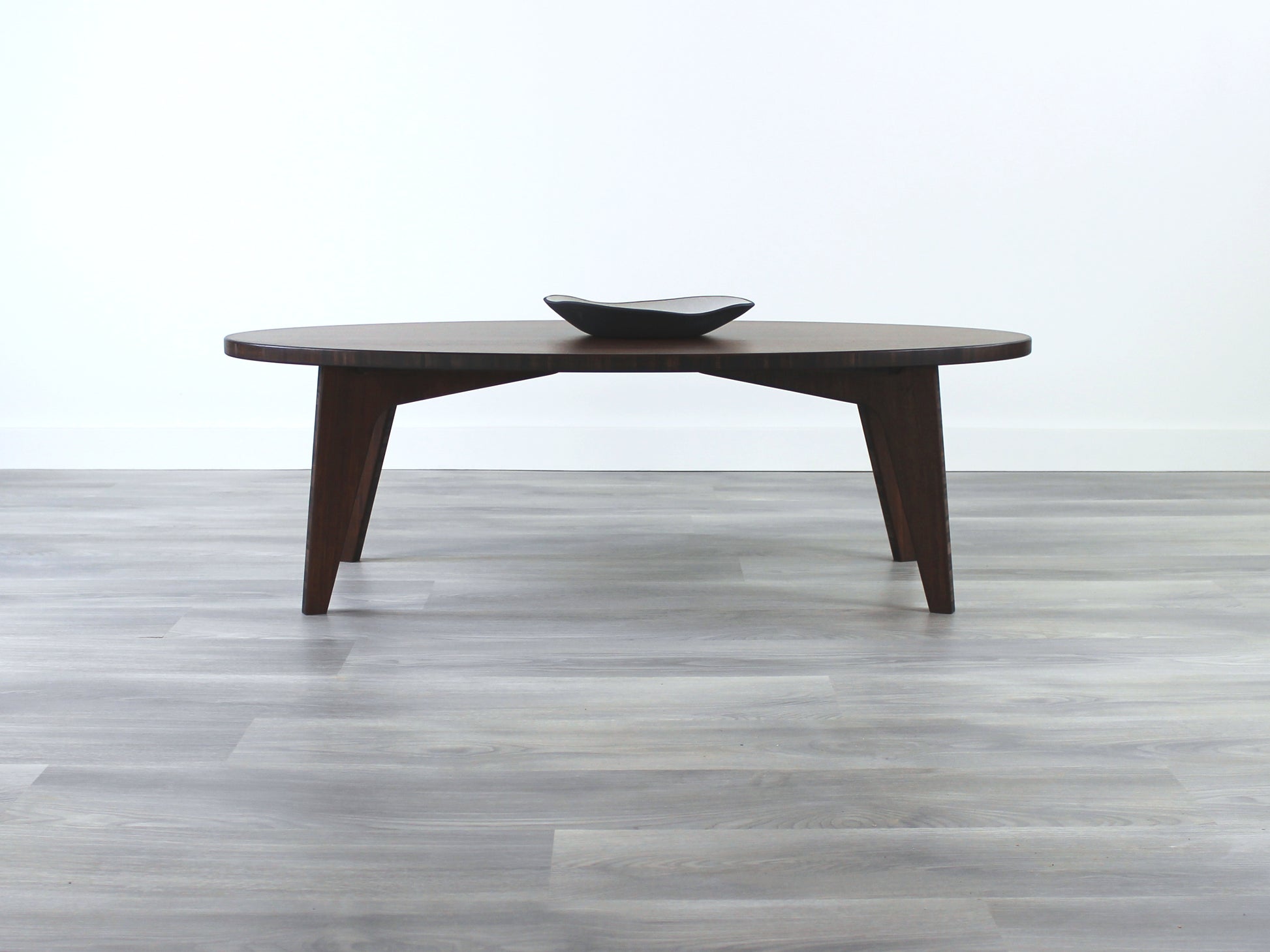 Oval bamboo table with a walnut color finish, featuring a Japandi style design, set on a grey floor with a white background. A small black pottery vessel is placed on the table top. 

mid century modern low table
midcentury modern coffee table
floor table
japan coffee table
japan furniture
japan table
bamboo low table