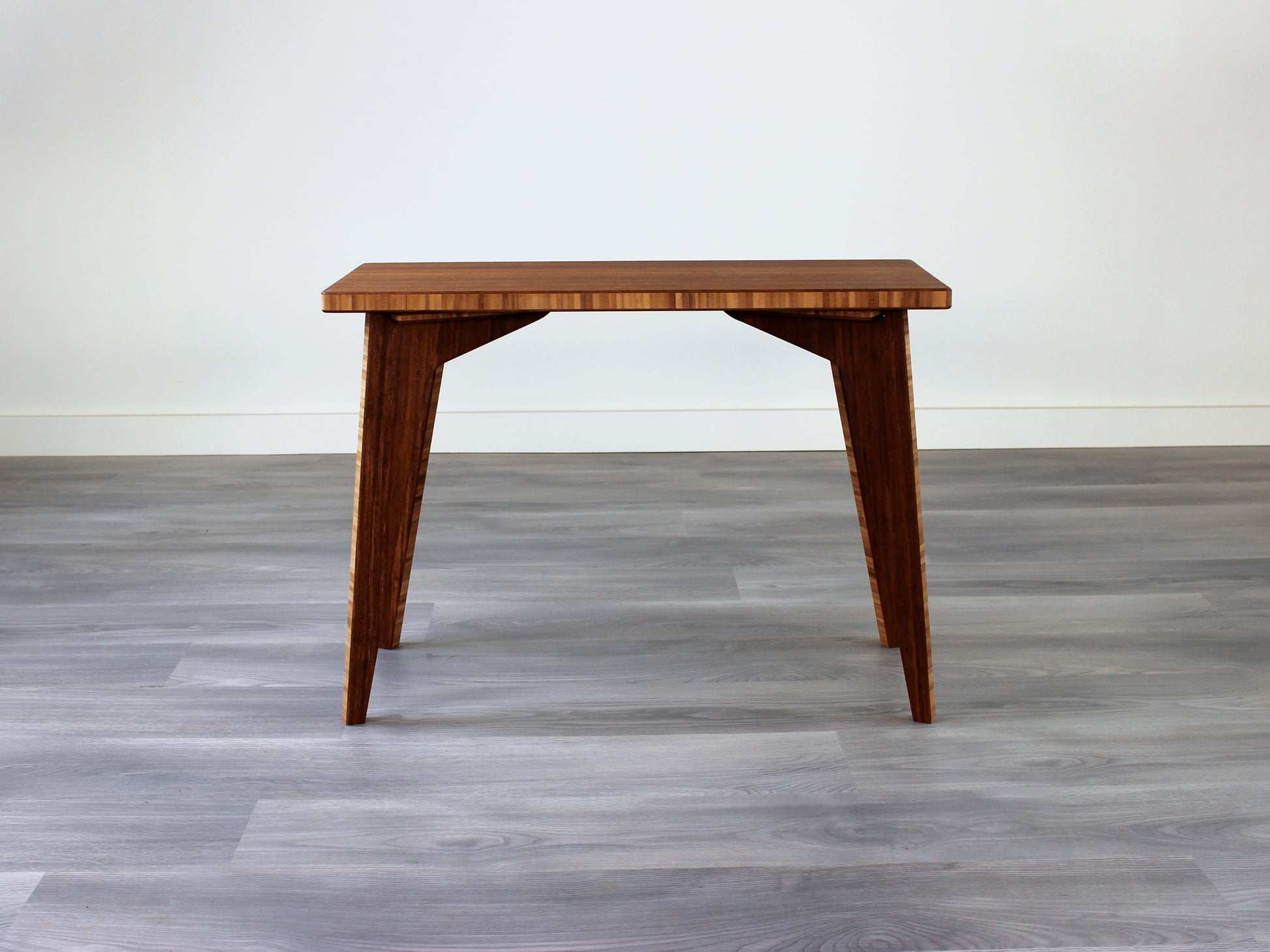 A rectangular side table with a chestnut finish bamboo top and legs, placed on a grey floor, with a white background. 
mid century
minimalist
Japanese inspired
coffee table
side table