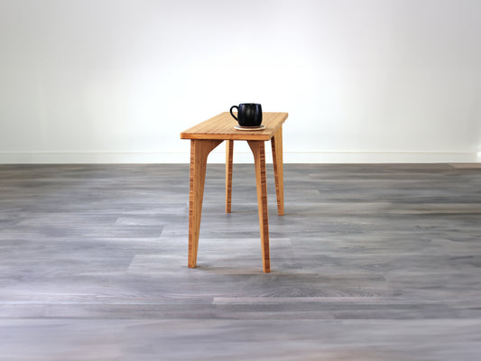 A rectangular side table with a natural finish bamboo top and legs, placed on a grey floor, with a white background. Black cup on top of the table.
mid century
minimalist
contemporary
coffee table
side table