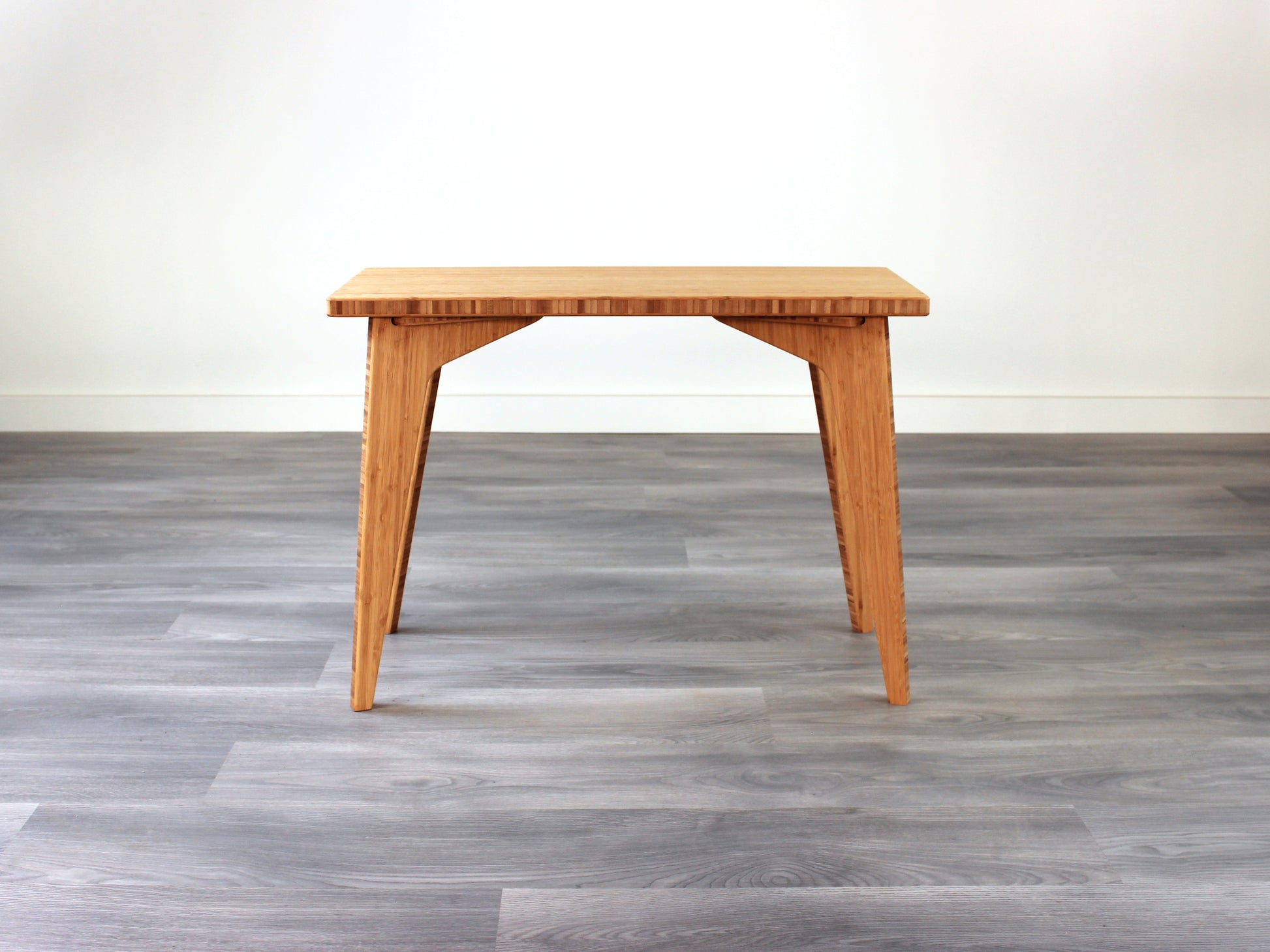 A rectangular side table with a natural finish bamboo top and legs, placed on a grey floor, with a white background. 
mid century
minimalist
contemporary
coffee table
side table