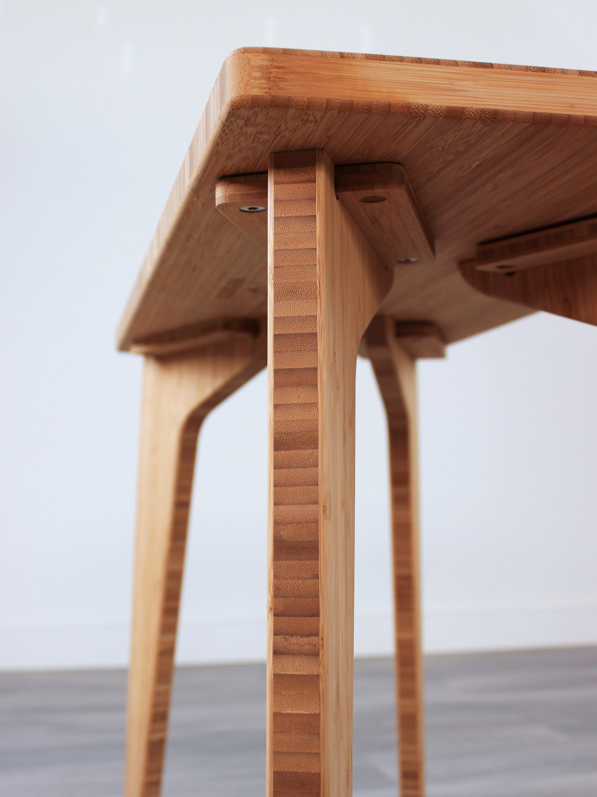 A rectangular side table with a natural finish bamboo top and legs, view of underside. Handmade bracket hardware, allows for leg removal/replacement. 
mid century
minimalist
chabudai
coffee table
side table
brackets 
removable hardware