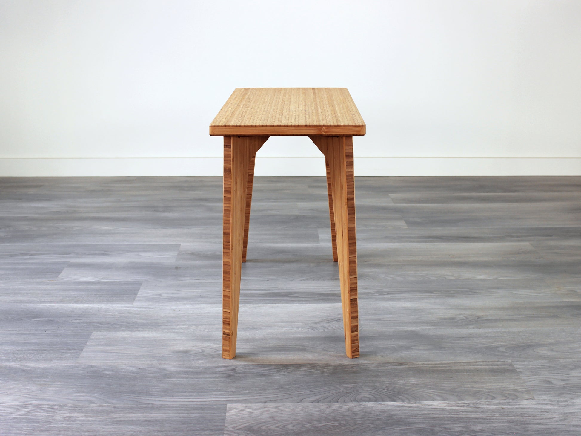 A rectangular side table with a natural finish bamboo top and legs, placed on a grey floor, with a white background. 
mid century
minimalist
contemporary
coffee table
side table