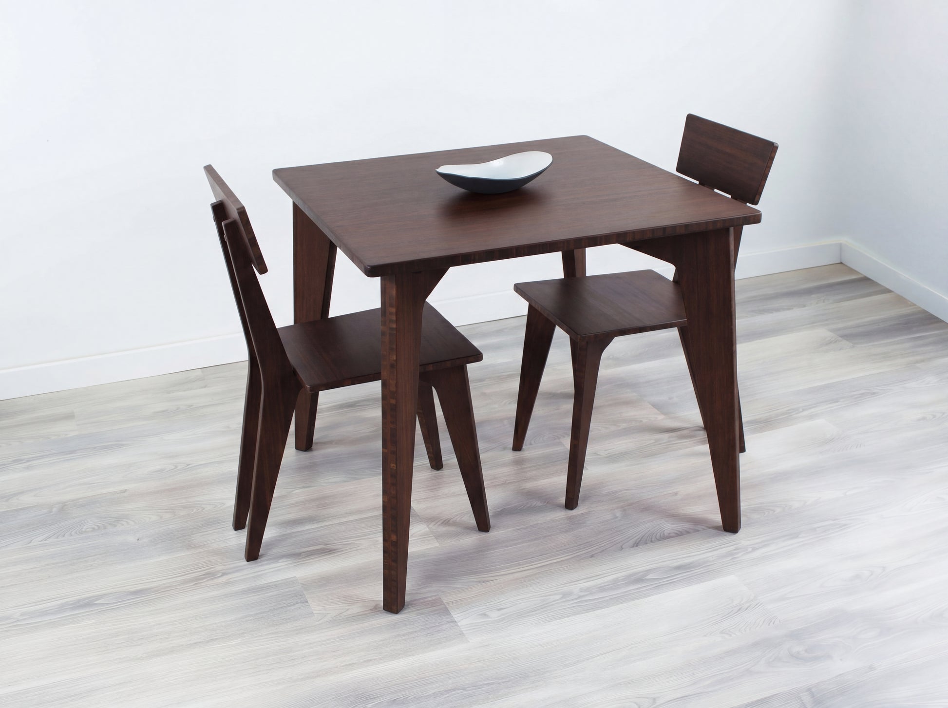 Bamboo dining table with four chairs on a light wooden floor.