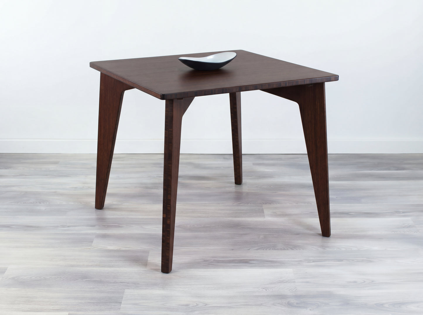 Bamboo table with a bowl on a gray floor and white wall