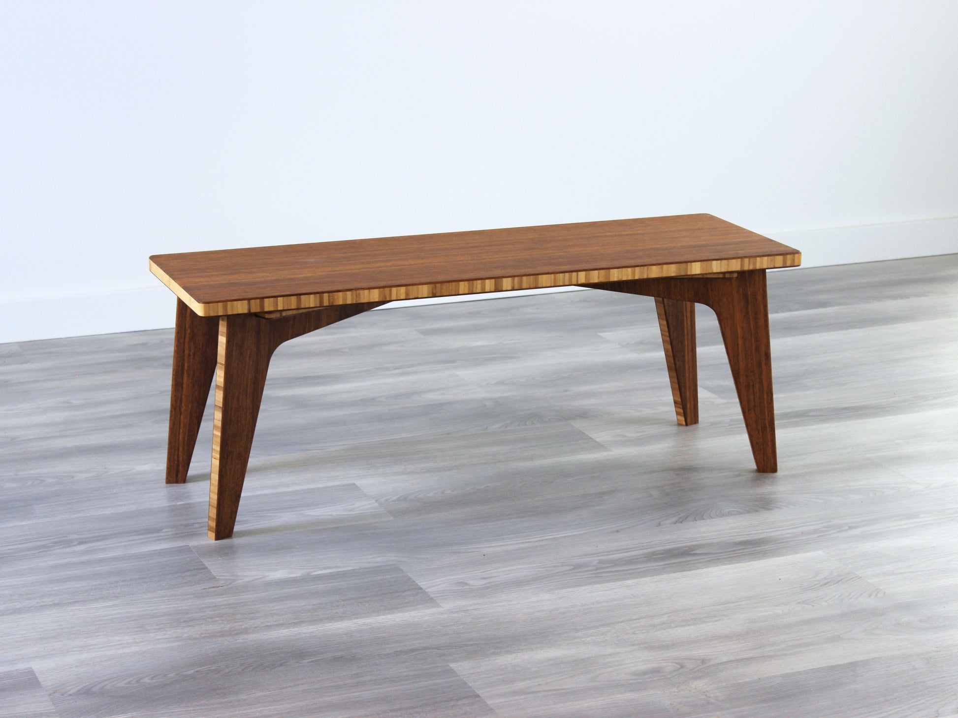 A small rectangular floor desk made of bamboo with a chestnut finish,  placed on a grey floor with a white wall in the background.
japanese furniture
japanese low table
mid century
minimalist
minimalist table
low desk 

