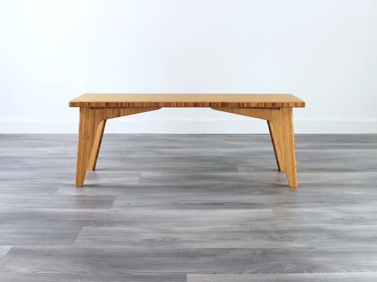 A small rectangular floor desk made of bamboo with a natural finish,  placed on a grey floor with a white wall in the background.
japanese furniture
japanese low table
mid century
minimalist
minimalist table
low desk 
