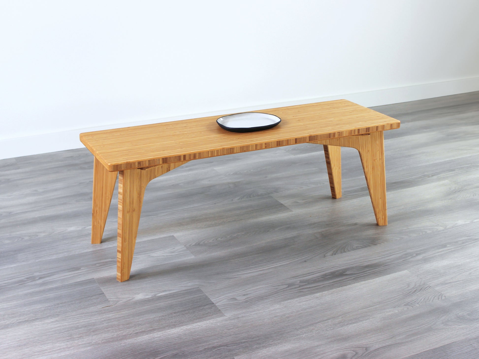 A small rectangular floor desk made of bamboo with a natural finish, small white and black pottery on the table face. All placed on a grey floor with a white wall in the background.
japanese furniture
japanese low table
mid century
minimalist
minimalist table
low desk 
tatami

