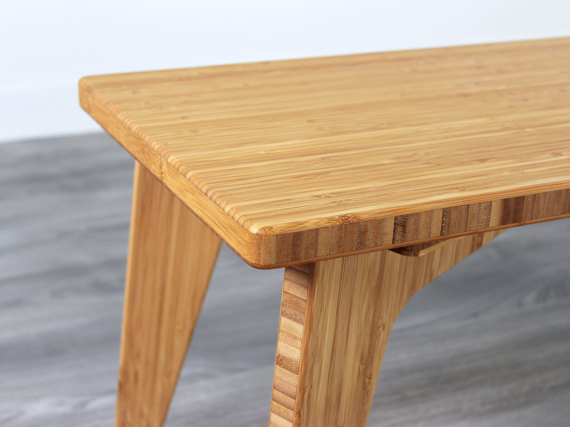 A close up of a small rectangular floor desk made of bamboo with a natural finish, placed on a grey floor with a white wall in the background.
japanese furniture
japanese low table
mid century
minimalist
minimalist table
low desk 
tatami
