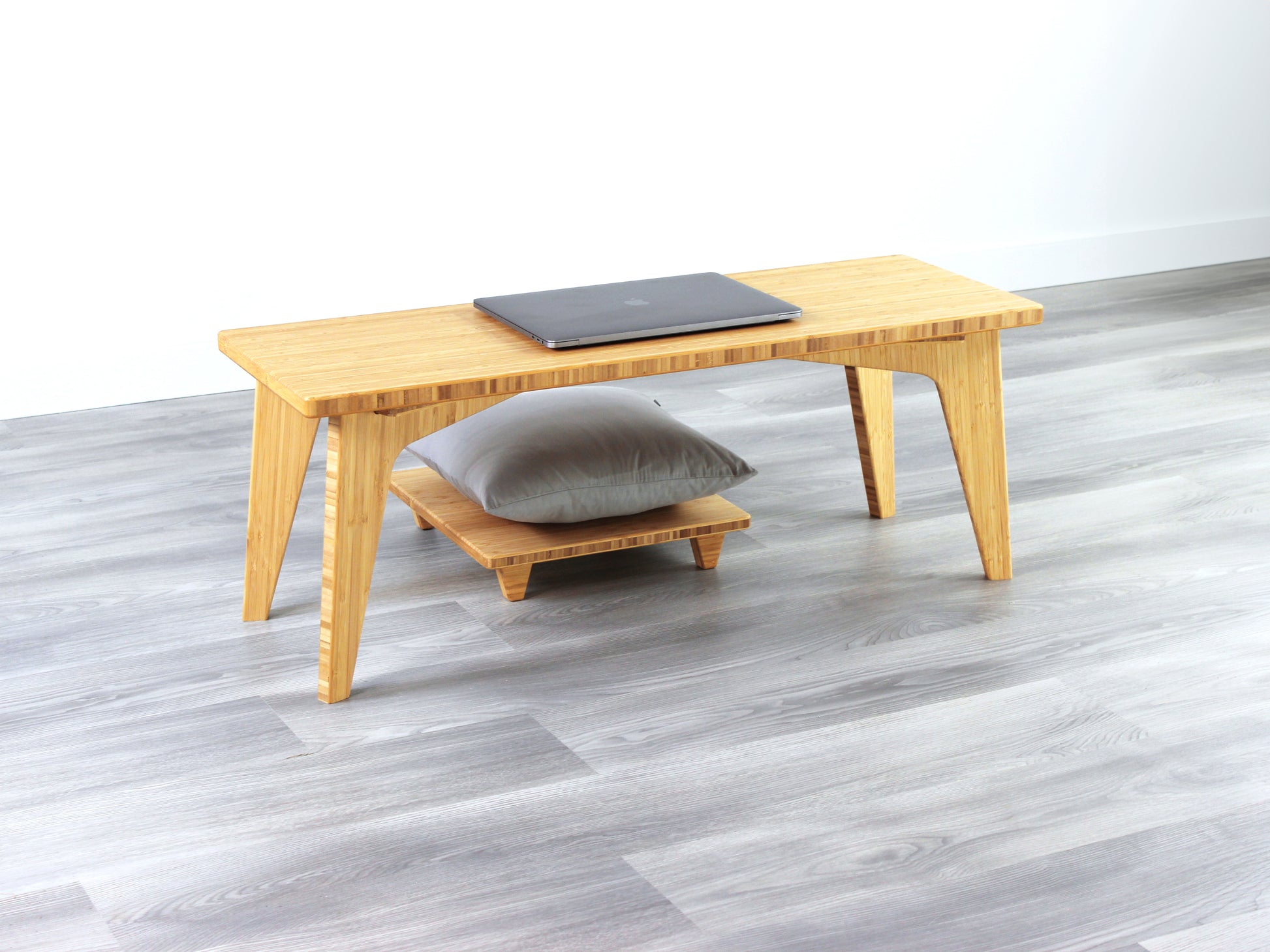 A small rectangular floor desk made of bamboo with a natural finish, a laptop on the table face with Floor Chair Posture set beneath. All placed on a grey floor with a white wall in the background.
japanese furniture
japanese low table
mid century
minimalist
minimalist table
low desk 
tatami