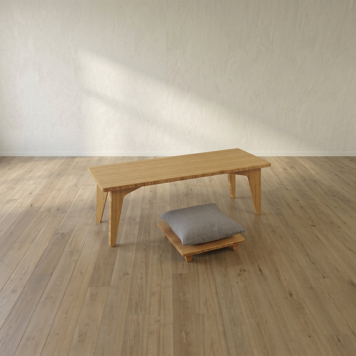 A small personal low bamboo desk and floor chair with cushion in a large open space.