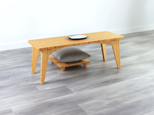 A small rectangular floor desk made of bamboo with a natural finish, featuring a single black piece of pottery on its top surface, placed on a grey floor with a white wall in the background. Floor Chair Posture placed beneath.

mid century, minimalist, minimalist table, modern, square coffee table, table, tatami, Floor chair, posture support, low chair, chestnut bamboo