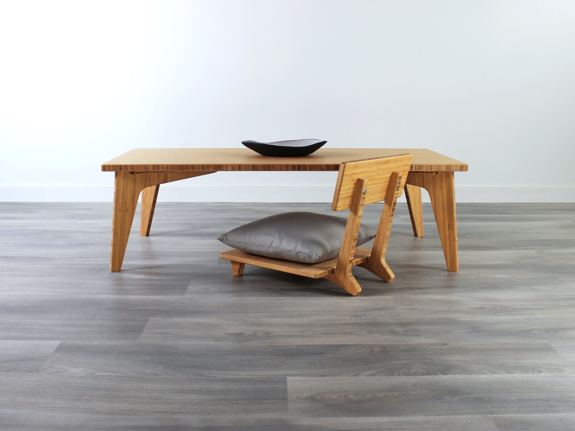 Small Rectangle Table Set - Chestnut, low table with Floor Chair Comfort set under with grey pillow. Set on a grey floor, against a white background. A small black pottery vessel is on the table top. 

low table, coffee table, dining table, floor desk, floor chair, floor seating, low dining table, chabudai, tatami, kotatsu, minimalist, minimalist table,
modern
