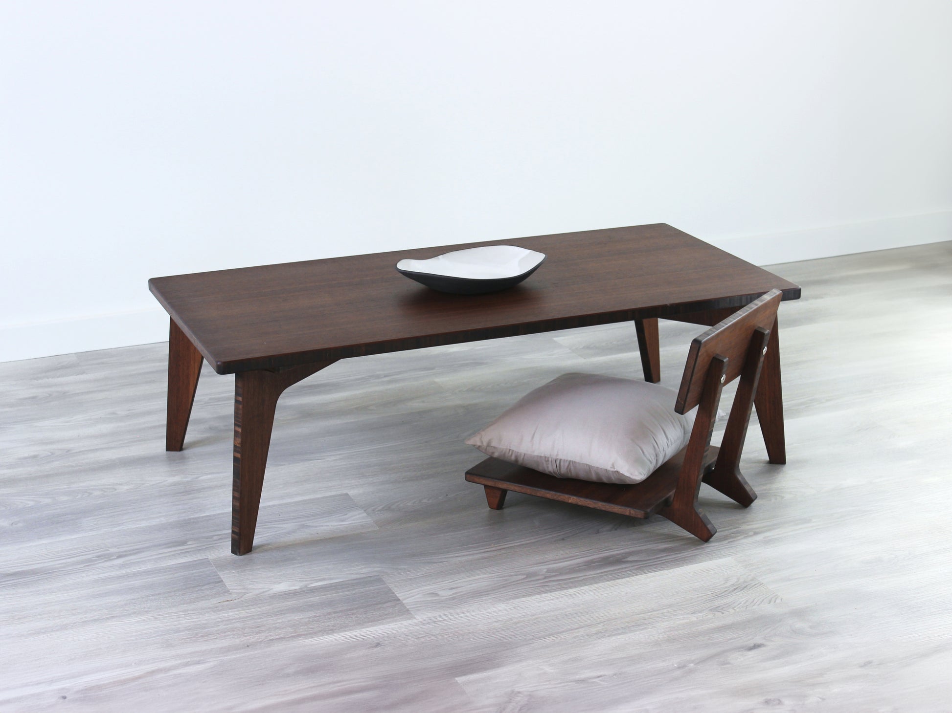 Small Rectangle Table Set - Walnut low table with Floor Chair Comfort set under with grey pillow. Set on a grey floor, against a white background. A small black pottery vessel is on the table top. 

low table, coffee table, dining table, floor desk, floor chair, floor seating, low dining table, chabudai, tatami, kotatsu, minimalist, minimalist table,
modern