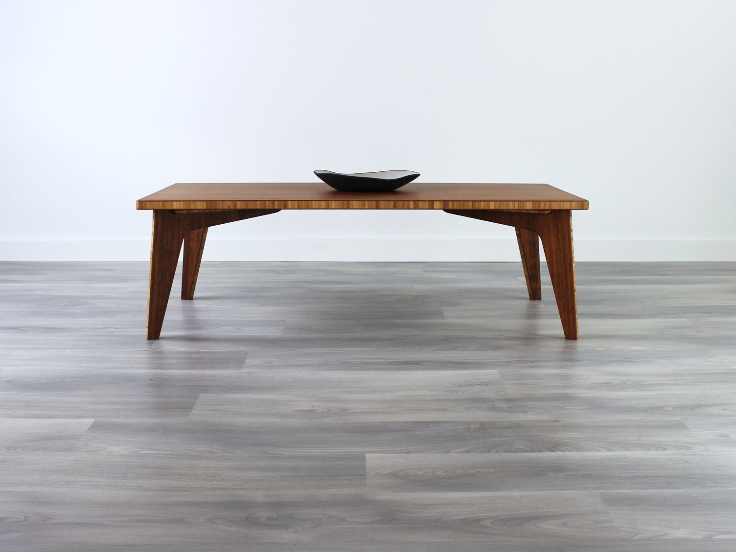 A small rectangular low table made of bamboo with a natural finish, placed on a grey floor with a white background. A small black pottery vessel is placed on the table top. 

japanese furniture
japanese low table
low coffee table
low dining table
low table
mid century
minimalist
minimalist table
modern
chabudai
