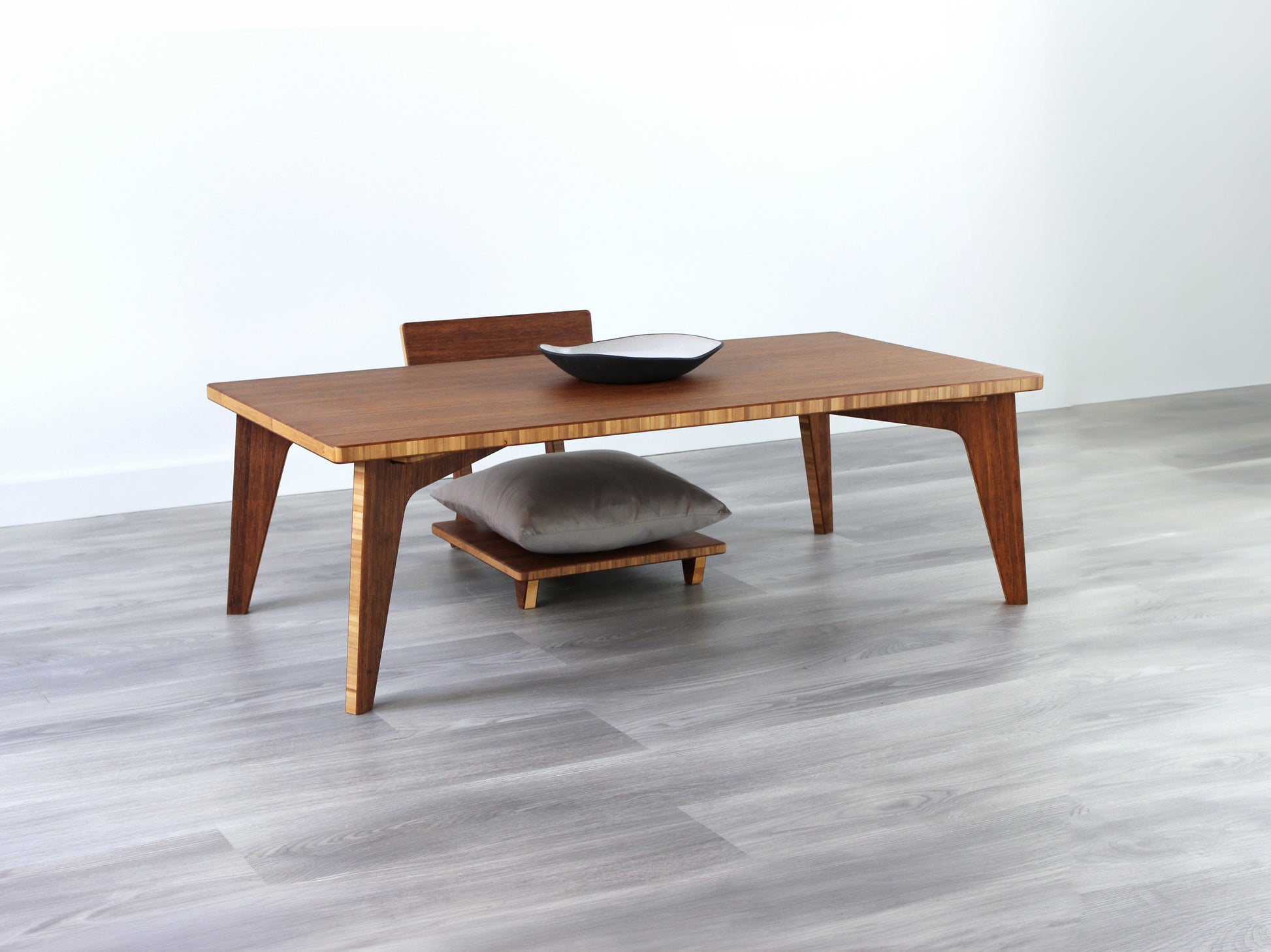 Small Rectangle Table Set - Chestnut, low table with Floor Chair Comfort set under with grey pillow. Set on a grey floor, against a white background. A small black pottery vessel is on the table top. 

low table, coffee table, dining table, floor desk, floor chair, floor seating, low dining table, chabudai, tatami, kotatsu, minimalist, minimalist table,
modern
