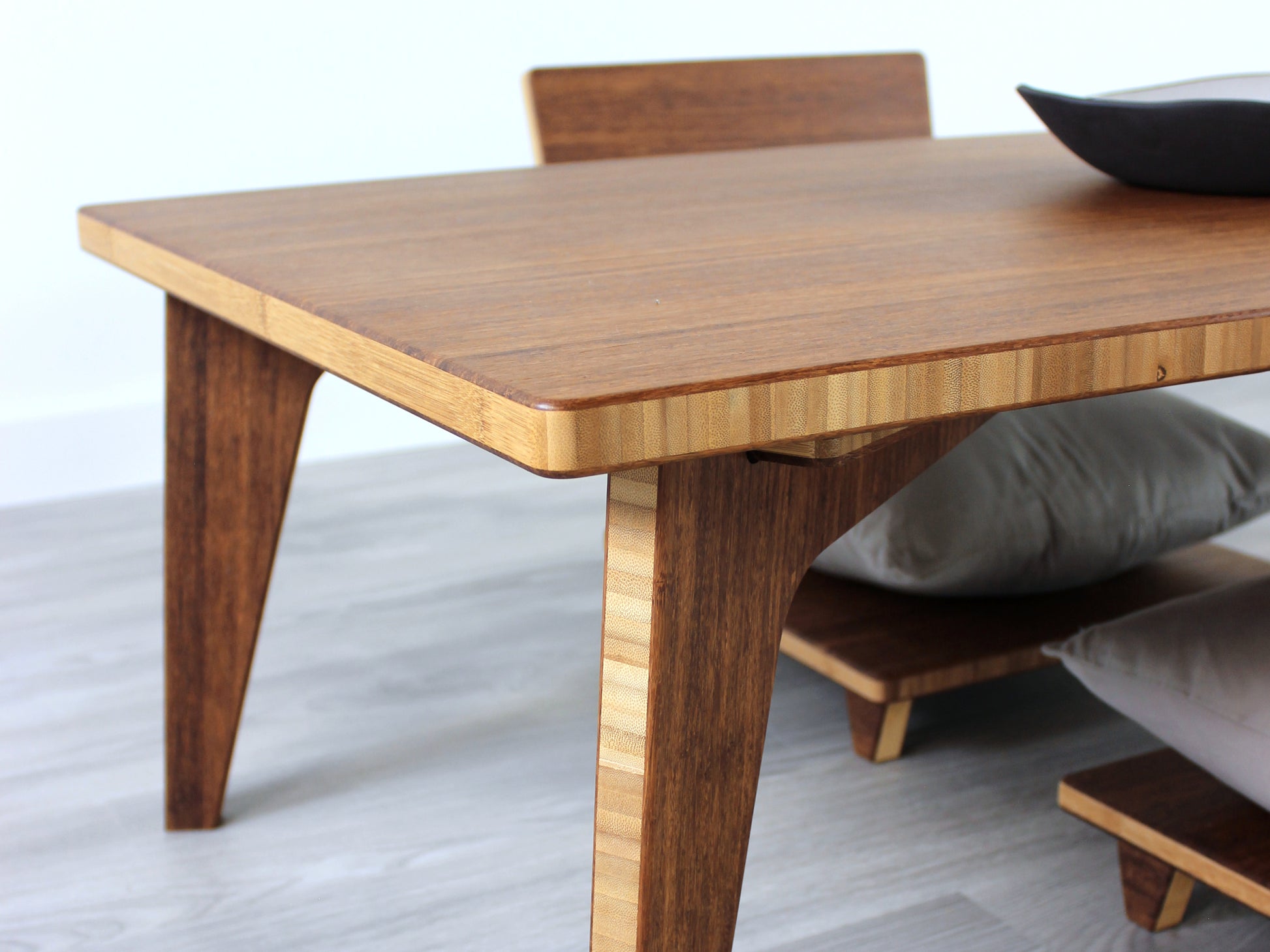 Small Rectangle Table Set - Chestnut, low table with Floor Chair Comfort set under with grey pillow. Set on a grey floor, against a white background. A small black pottery vessel is on the table top. 

low table, coffee table, dining table, floor desk, floor chair, floor seating, low dining table, chabudai, tatami, kotatsu, minimalist, minimalist table,
modern