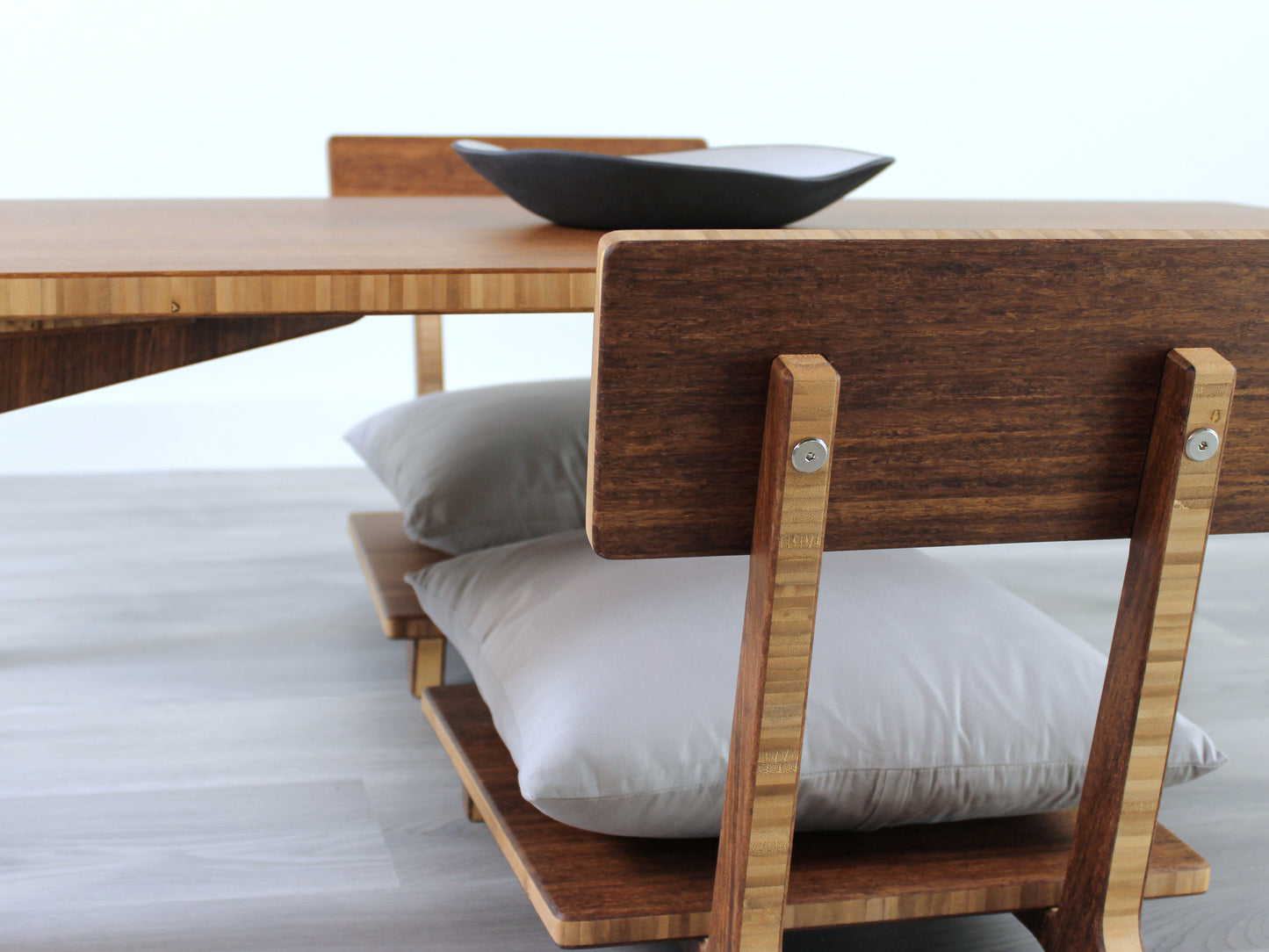 Small Rectangle Table Set - Chestnut, low table with Floor Chair Comfort set under with grey pillow. Set on a grey floor, against a white background. A small black pottery vessel is on the table top. 

low table, coffee table, dining table, floor desk, floor chair, floor seating, low dining table, chabudai, tatami, kotatsu, minimalist, minimalist table,
modern
