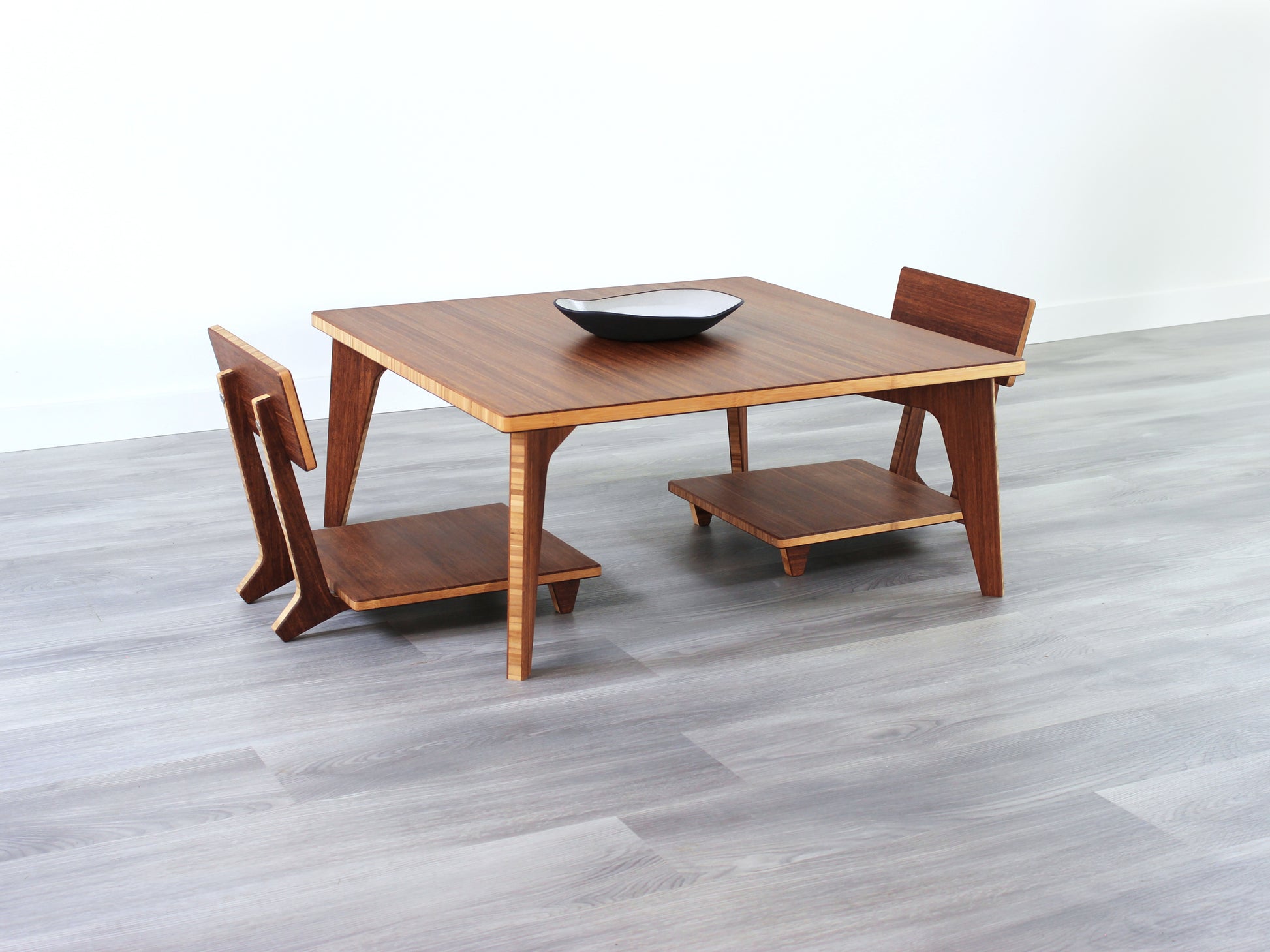 Small Square Table Set in chestnut finish. Two Floor Chair Comfort  are placed below. A small black pottery vessel is placed on top of the table. 

sustainable bamboo, renewable bamboo, solid bamboo, eco-friendly furniture, zero-waste, carbon neutral, natural materials, natural-based finish, repairable furniture