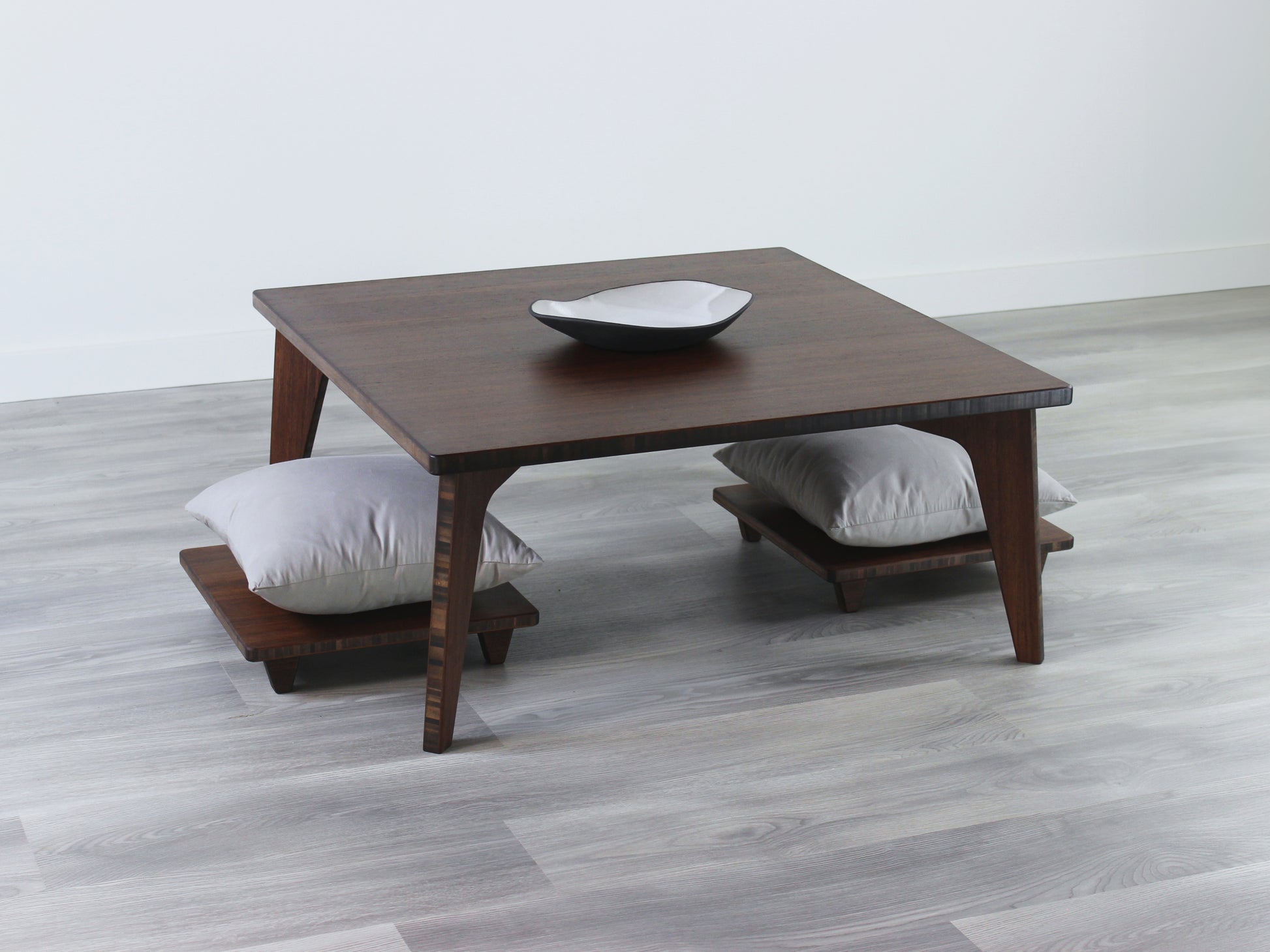 Small Square Table Set in walnut finish. Two Floor Chair Posture with grey pillows are placed below. A small black pottery vessel is placed on top of the table. 

sustainable bamboo, renewable bamboo, solid bamboo, eco-friendly furniture, zero-waste, carbon neutral, natural materials, natural-based finish, repairable furniture