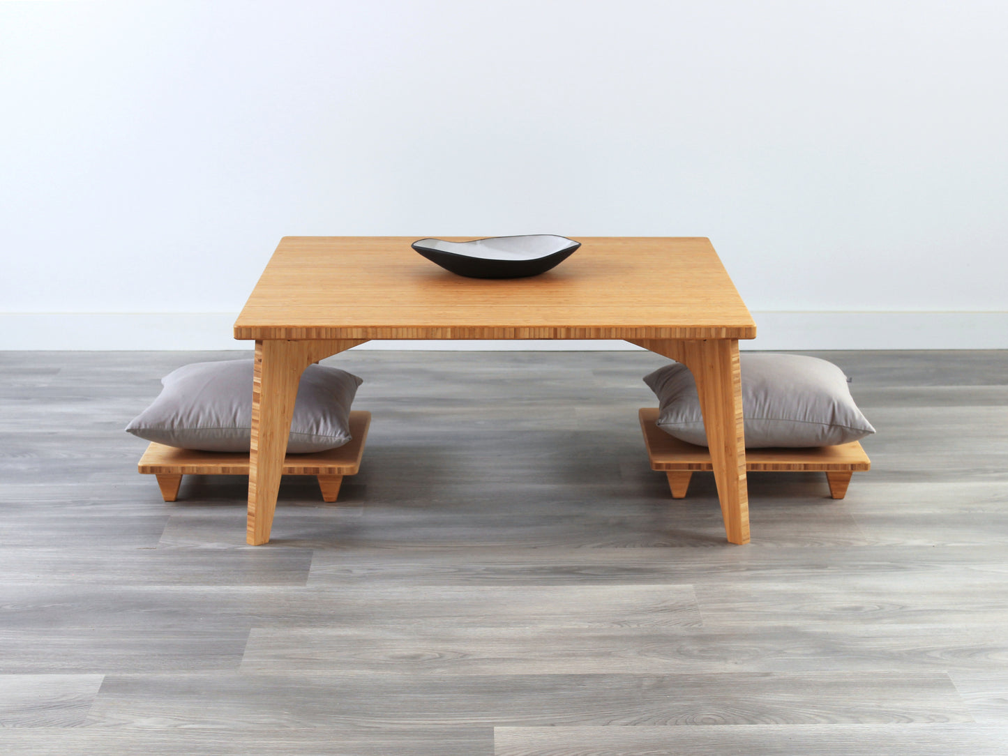 Small Square Table Set in natural finish. Two Floor Chair Posture with grey pillows are placed below. A small black pottery vessel is placed on top of the table. 

sustainable bamboo, renewable bamboo, solid bamboo, eco-friendly furniture, zero-waste, carbon neutral, natural materials, natural-based finish, repairable furniture