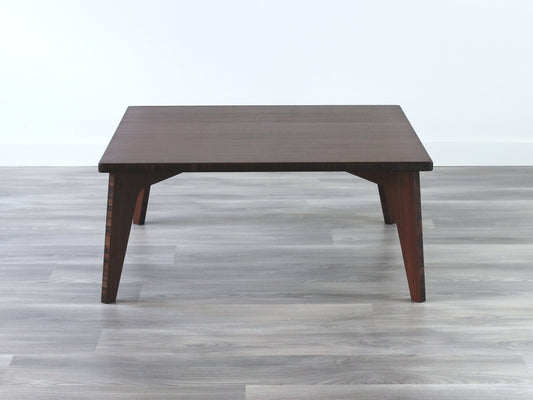 A small square, walnut bamboo table with visible wood grain, placed on a grey floor.