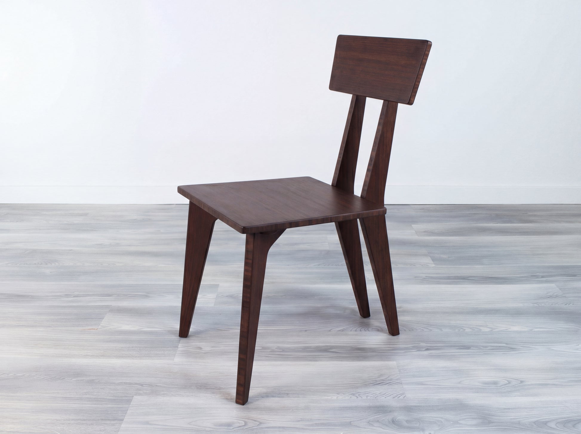 Bamboo chair on a gray wooden floor with a white wall background