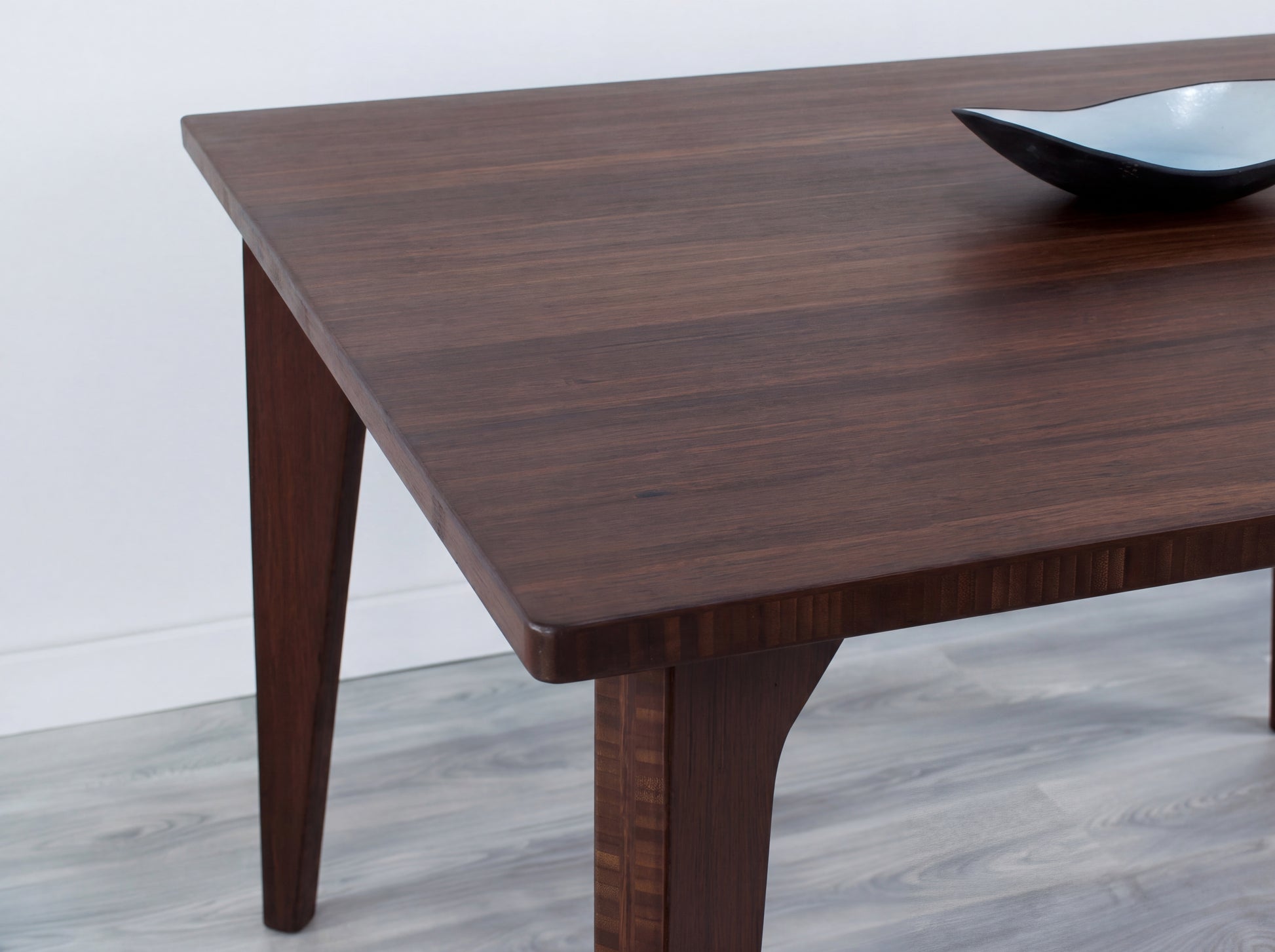 Bamboo table with a bowl on a light gray floor and white wall background