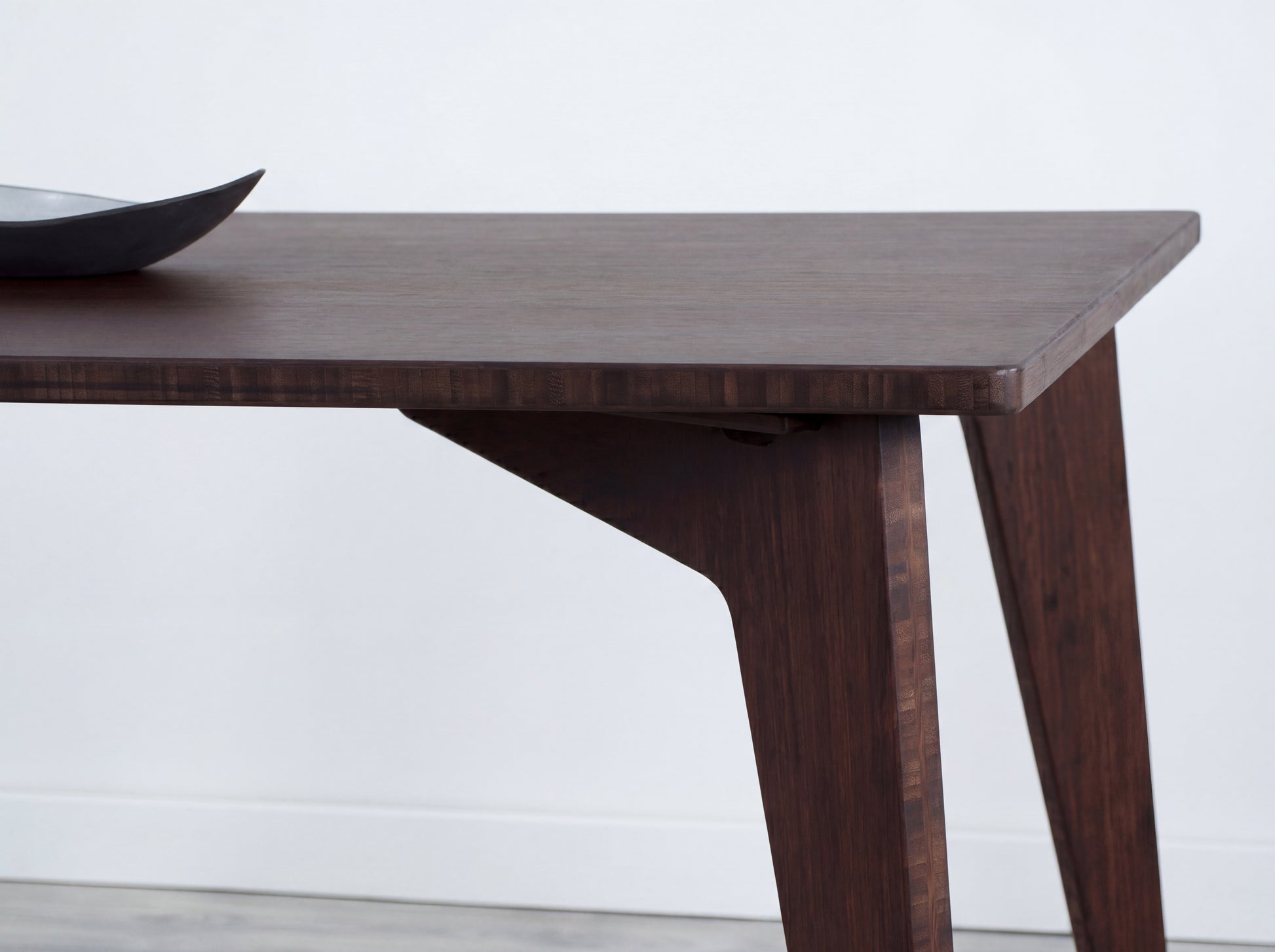 Walnut bamboo dining table on a while background with black bowl on top